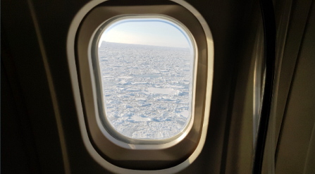 Photo of looking out of a plane window with floating sea ice clearly visible close below